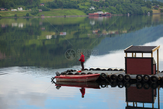 在阴云的一天站在挪威湾码头的渔夫图片