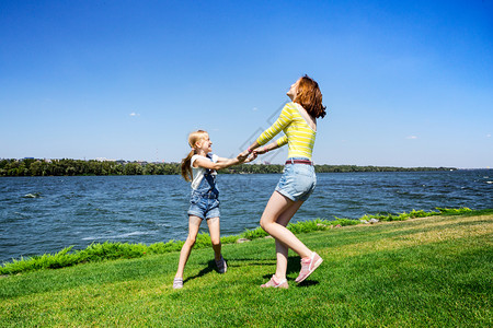 假期两姐妹在河边草地上开心的玩耍图片