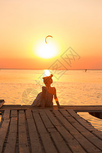 在海船和日落背景的码头上的女孩图片