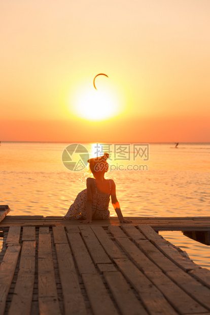 在海船和日落背景的码头上的女孩图片