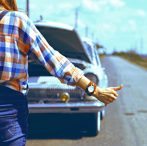 在田野路上搭便车的年轻妇女图片
