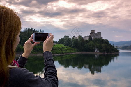 女孩用智能手机拍摄城堡的图片