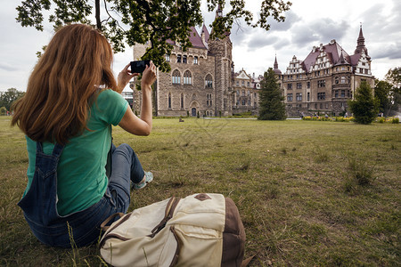 女孩用智能手机拍摄城堡的图片