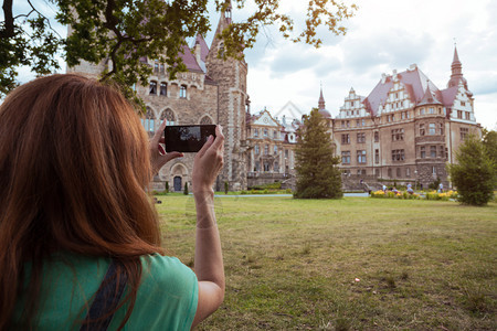 女孩用手机拍摄城堡图片