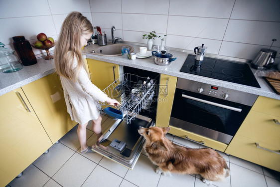 小女孩在厨房洗碗机里盘子图片