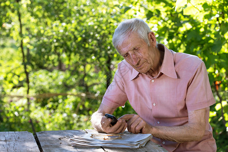 坐在花园桌子上讲电话的老人图片