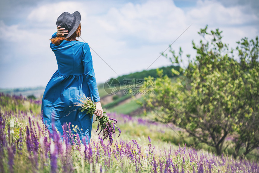 夏天美丽的女孩在草地上带着一束野花和传统的乌拉尼风景图片