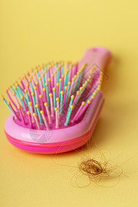 粉红色梳子和黄背景下垂头发图片