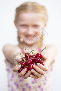 夏天微笑的女孩手里握着成熟的红樱桃图片