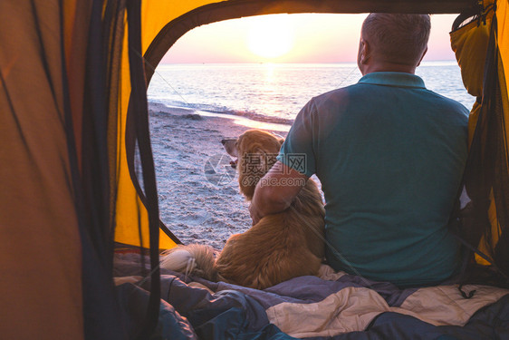 在帐篷里坐着的男人和狗图片