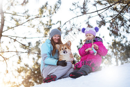 母亲和女儿小狗在雪地里坐着图片