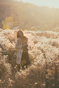 古老的秋天女孩与古老的摄像头在日落时走田野中图片