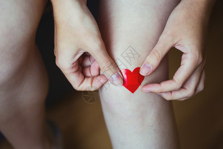 女孩在腿上用红心涂药膏图片