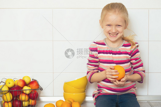 在厨房里手握着橘子小女孩图片
