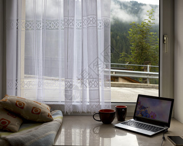 枕头格子笔记本电脑窗台上的咖啡外风景图片