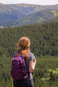 女孩背着包在山地和森林徒步旅行图片