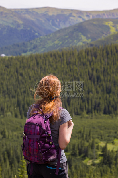 女孩背着包在山地和森林徒步旅行图片