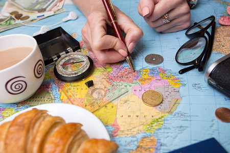旅行计划背景旅行要带什么妇女手和反光相机钱硬币羊角面包咖啡笔指南针太阳镜图片