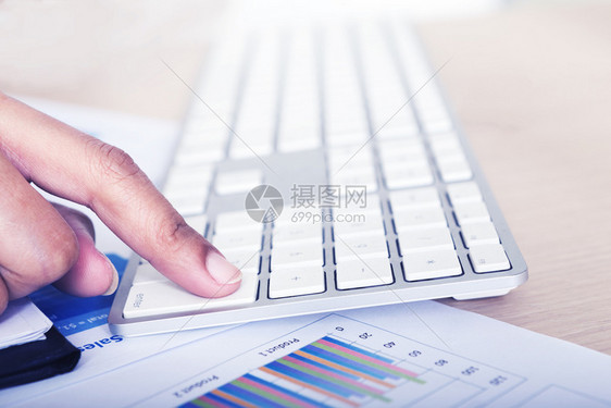 使用纸质图表和在商业工作场所键盘上输入企业财务分析概念图片