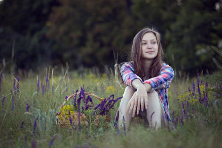 女青少年独自坐在草地上靠近有圣的篮子图片