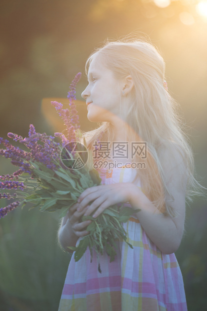 夏天美丽的女孩在草地上带着一束花图片