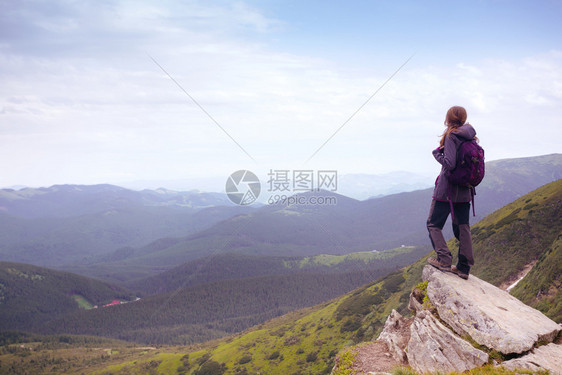 女孩背着包在山地和森林徒步旅行图片