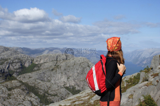 女孩远足者站在岩石上看着山图片