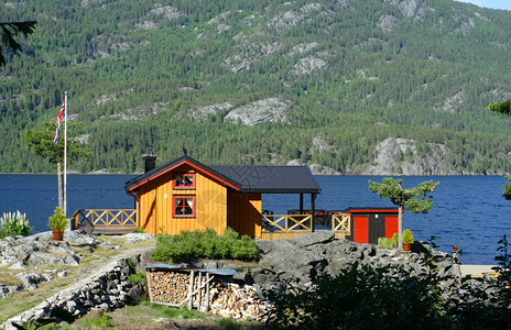 在湖边和远处的山上站立着传统的挪威木制房屋图片
