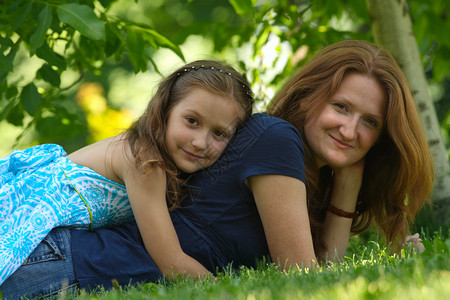 母亲和女儿躺在公园的草地上背景图片