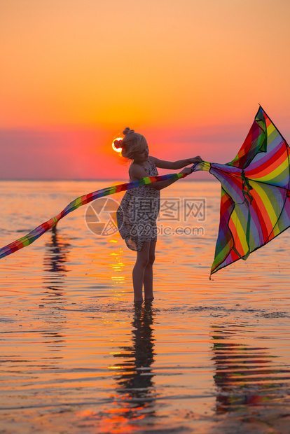 女孩日落时在海边放风筝图片