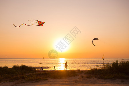 女孩在日落时海边放风筝图片