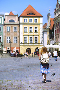 女孩在光亮城市波兹南的主要正方圆边行走图片