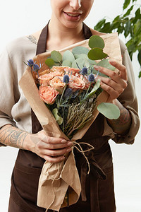 妇女手与纹身握着花玫瑰束祝贺灰色背景母亲和日的概念关闭以鲜花玫瑰在浅色背景的纸上以创造花束盛装女孩卉祝贺卡图片