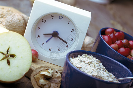 健康早餐钟表牛奶燕麦红莓坚果木桌上的苹图片