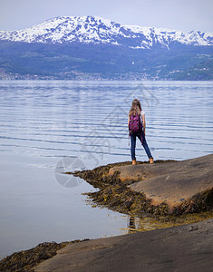女孩徒步旅行者背包站在岸边的硬马格夫乔登诺威图片