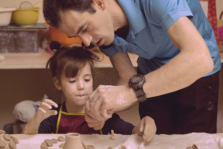 陶器车间与他父亲一起用泥土雕塑的小女孩图片