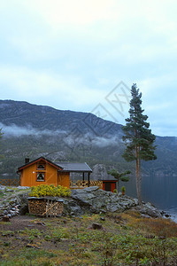 在湖边和远处的山上站立着传统的挪威木制房屋图片