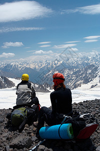 两名登山者坐在岩石上看着山地全景图片