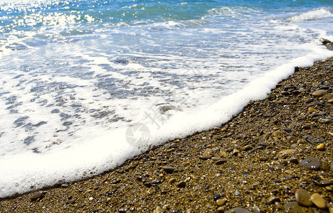 海浪泡沫在冰封的海岸上浪图片