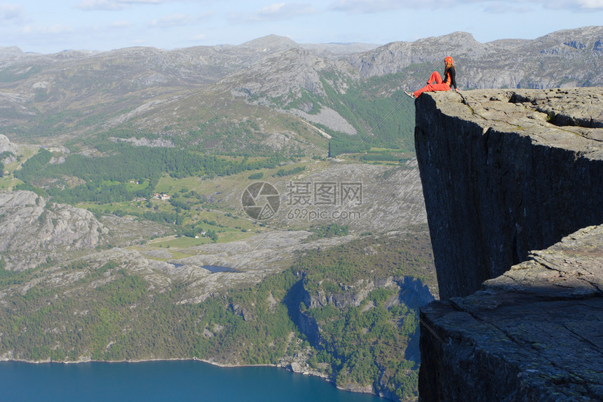 女孩徒步旅行者坐在悬崖边的上看着山图片