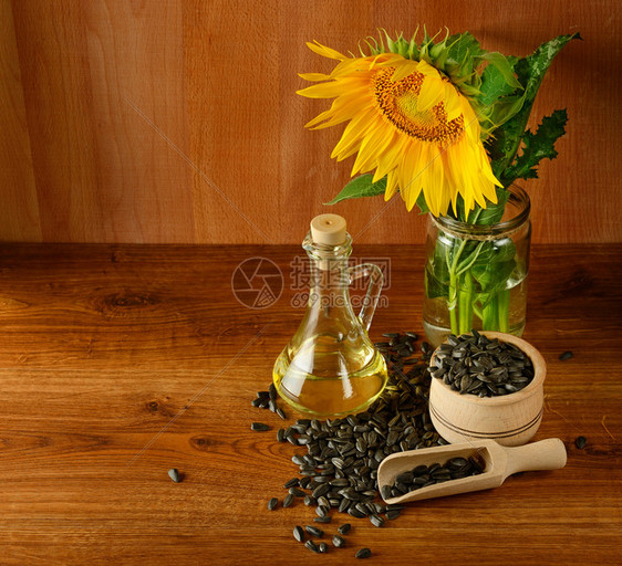 木制背景的种子油和向日葵花朵图片