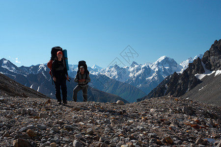 两个徒步旅行者上山蓝天空在背景中图片