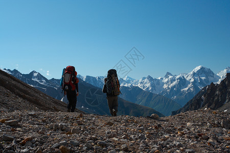 两个徒步旅行者上山蓝天空在背景中图片