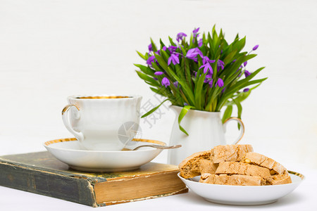 花瓶里有雪滴桌上一杯茶和饼干图片