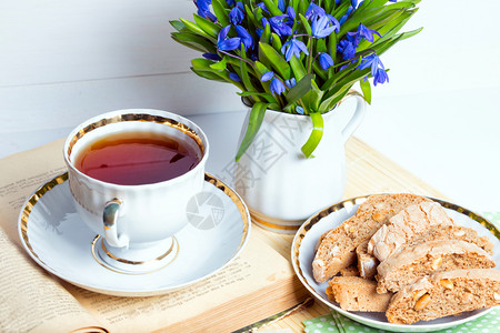 花瓶里有雪滴桌上一杯茶和饼干图片