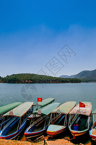 著名的传统木制旅游船在Tiyenlam湖或位于dltvienam的hotuyenlamke或ho春季有蓝天和山图片