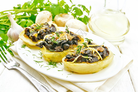 马铃薯加上蘑菇煎洋葱和芝士放在厨房毛巾上的菜盘中油装在熟机鹦鹉大蒜和木板上的叉子图片
