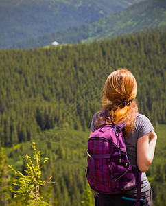 青年女孩背着包徒步旅行在山地和森林之间图片