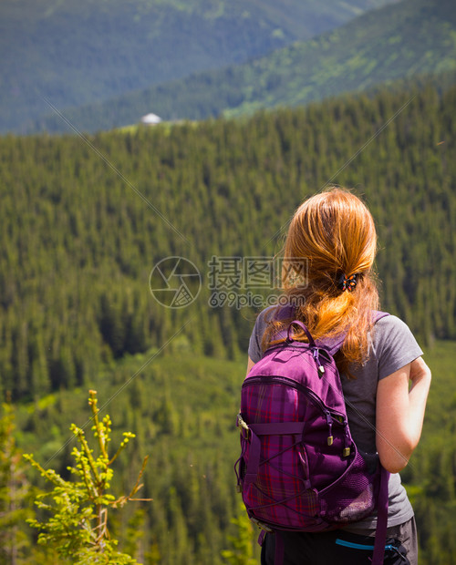 青年女孩背着包徒步旅行在山地和森林之间图片