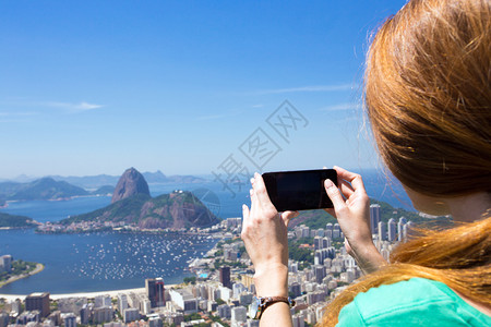 观光女游客用智能手机拍下一张照片图片